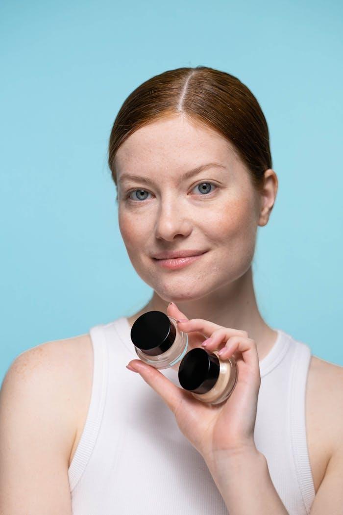 Woman in white tank top holding two cosmetic products 8129916.jpeg